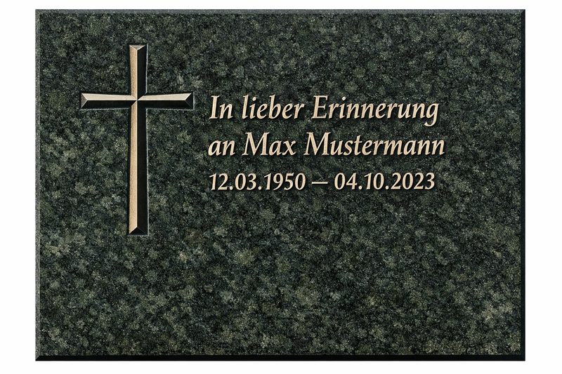 Beispiel für Keilnut-Gravur: 'In lieber Erinnerung an Max Mustermann' auf einer Diabas‑Tafel (Hessisch Neugrün). Die V‑förmige Rille mit Kreuz und Schrift zeigt die 90°‑Vertiefung und harmonische Platzierung.